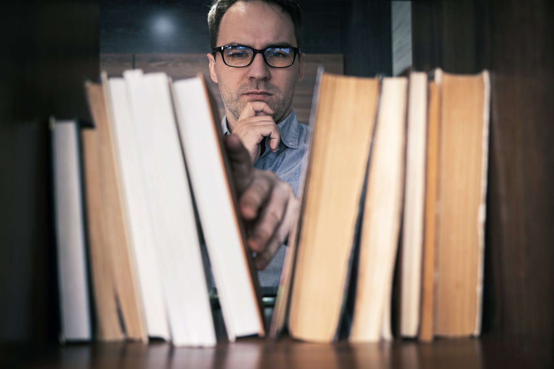 Muž vyberajúci knihu. - AI - Majstrovstvá produktivity s umelou inteligenciou